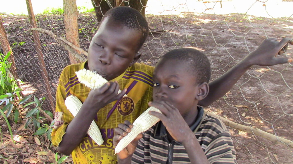 Children from Faith Learning Center in Boma, South Sudan eat from their harvest.